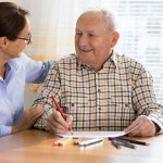 woman talking with senior man while he's writing on paper